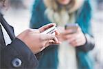 Close up of two young women texting on smartphones, Lake Como, Como, Italy