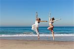 Two young female dancers leaping mid air on beach