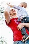 Father holding son, son giving father a high five, low angle view