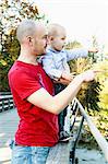 Father and son standing on bridge, looking at view, rural setting