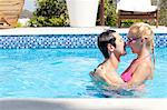 Mid adult couple in outdoor pool, kissing