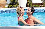 Mid adult couple in outdoor pool, laughing