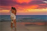 Couple standing on beach at sunset, Ari Atoll, Maldives