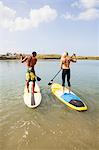 Rear view of couple standup paddleboarding, Carlsbad, California, USA