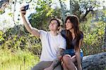 Young couple taking smartphone selfie in park