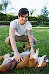 Portrait of young man in park playing with bulldog