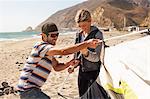 Couple setting up tent on beach, Malibu, California, USA