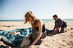 Couple setting up tent on beach, Malibu, California, USA