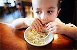Boy eating noodles in restaurant
