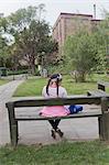 Young girl sitting on bench, rear view