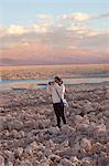 Young girl taking photograph of arid landscape of Salar de Atacama, San Pedro, Atacama, Chile