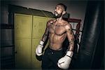 Tattooed male boxer poised wearing boxing gloves in gym