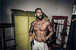 Tattooed male boxer with skipping rope in gym