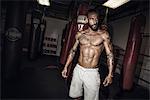 Tattooed male boxer poised looking sideways in gym