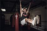 Male boxer training on bar with gritted teeth in gym