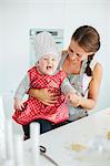 Smiling mother with baby daughter in kitchen