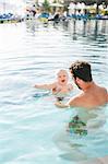 Father playing with baby in swimming-pool