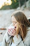 Young woman having drink on beach