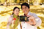 Senior Japanese couple taking pictures in a city park in Autumn