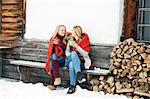 Two young female friends drinking coffee outside wooden cabin