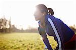 Mature female runner in field taking a break