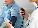 Doctor reading blood pressure of young boy in clinic