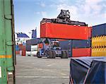 Stacker lifting shipping container in port, Grimsby, England, United Kingdom