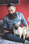 Young bearded man using smartphone on bed