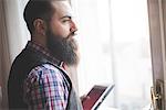 Young bearded man using digital tablet in room