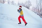 Boy running up snow covered hill, Hemavan,Sweden