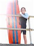 Portrait of boy nipper (child surf life savers) leaning against railings in sunlight, Altona, Melbourne, Australia