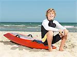 Portrait of confident boy nipper (child surf life savers) sitting on surfboard, Altona, Melbourne, Australia