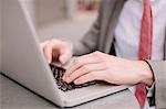 Hands of young city businessman typing on laptop at sidewalk cafe