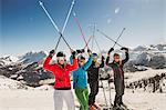 Portrait of skiers on slope, holding ski poles in the air