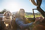 Mature woman and dog, in convertible car