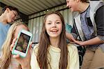 Girl holding up smartphone selfie of friends in shelter