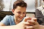 Smiling boy reading smartphone text message