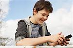 Smiling teenage boy reading smartphone text message