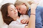 Two girls lying on bed with eyes closed