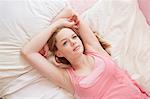 Girl lying on bed gazing upwards