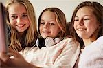 Three girls on sofa using digital tablet