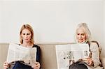 Senior and mid adult women reading newspapers