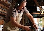 Boat builder sanding wood in workshop