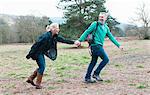 Hiking couple holding hands and running in field