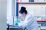 Young female scientist in lab pipetting sample