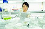 Female scientist using digital tablet in plant sample lab