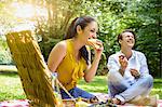 Young couple sitting eating picnic laughing