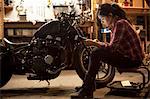 Female mechanic working on motorcycle in workshop