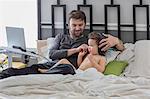Father putting headphones on toddler daughter in bed