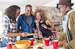 Four adult friends  eating party food in kitchen